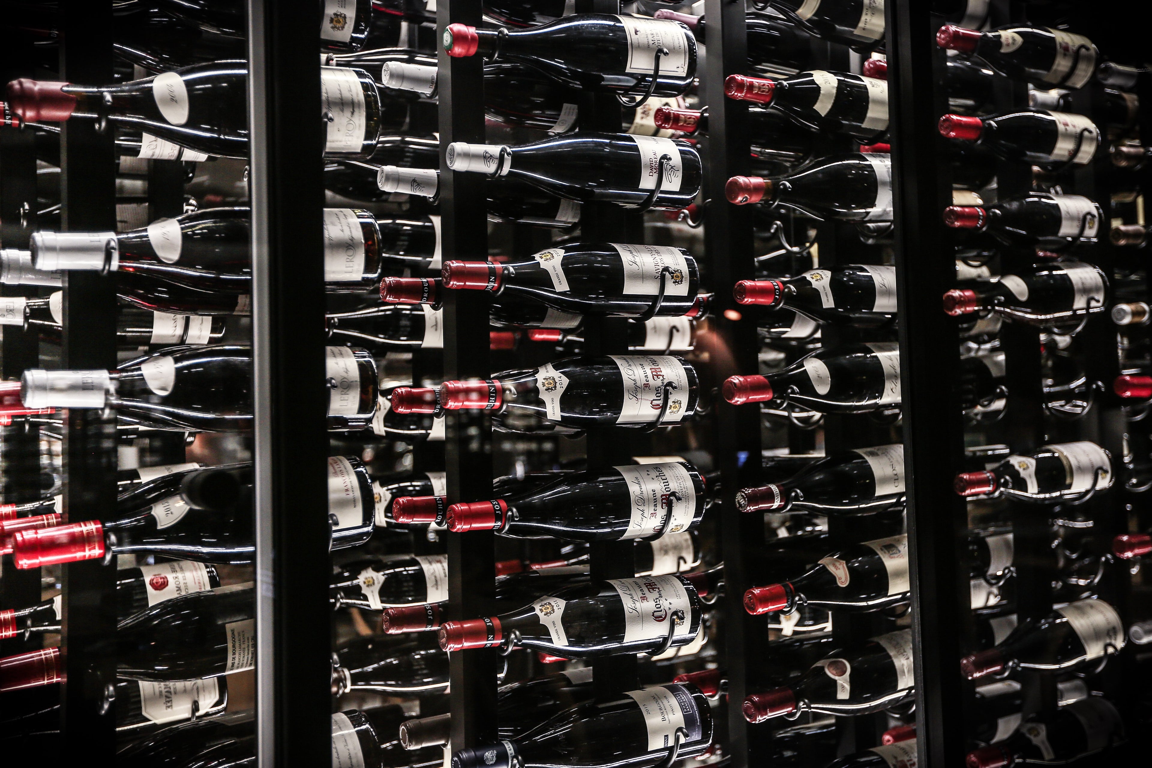 Exklusive Weine aus den besten Anbaugebieten – Bordeaux, Toskana, Napa Valley auf in einem edlen Weinregal bei Maniola Wines