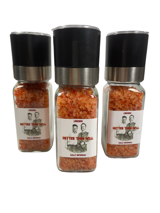 Gewürzmühlen aus Glas mit rosafabenem Chillisalz auf weißem Hintergrund